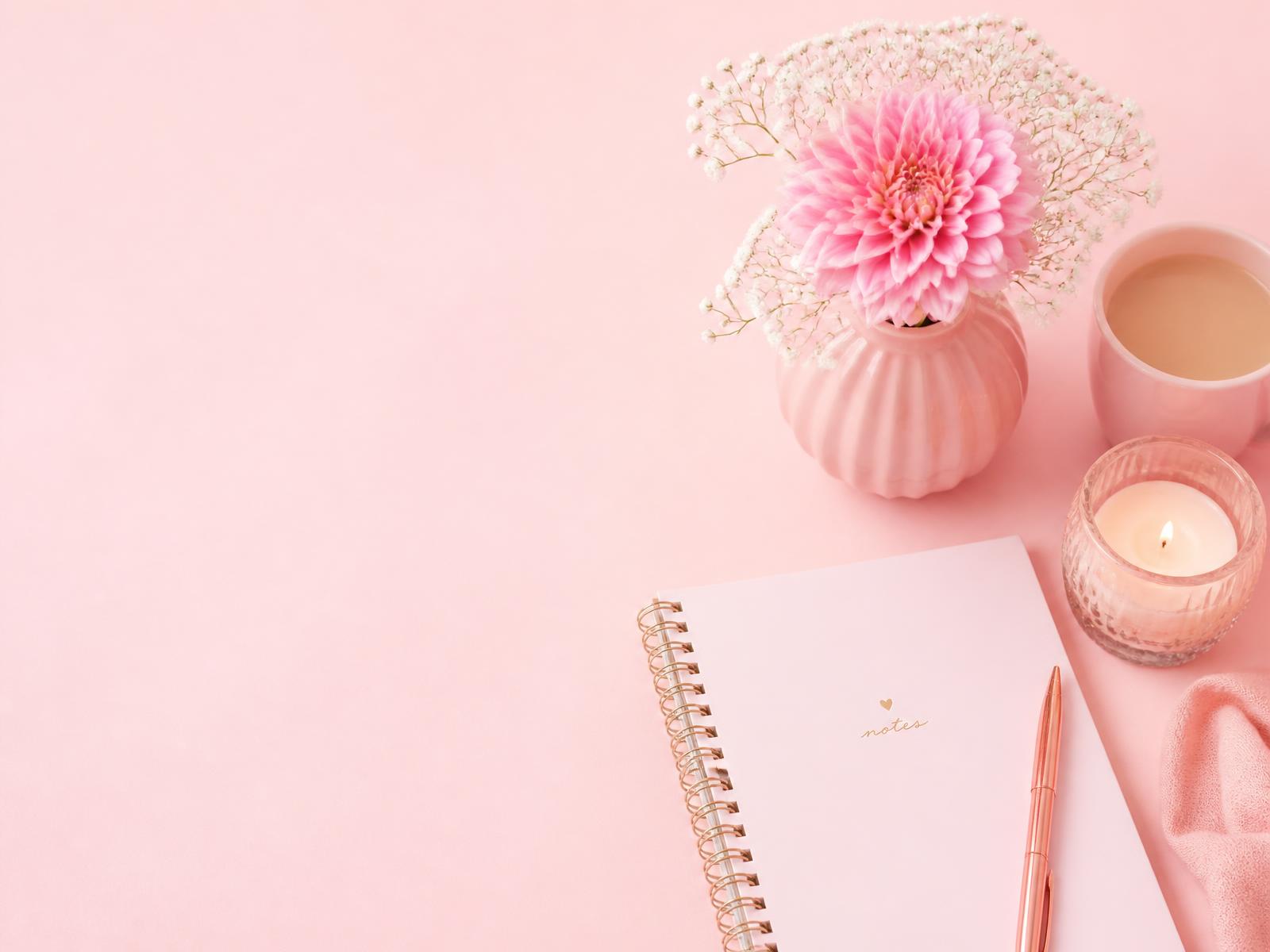 Bureau rose avec carnet, fleurs et bougie